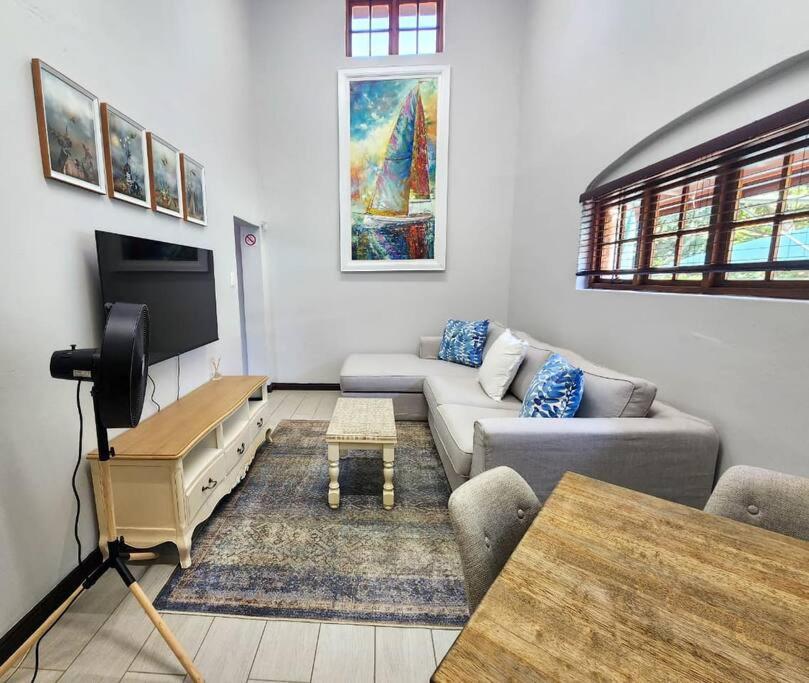 uma sala de estar com um sofá e uma televisão em Margate Manor em Pretoria