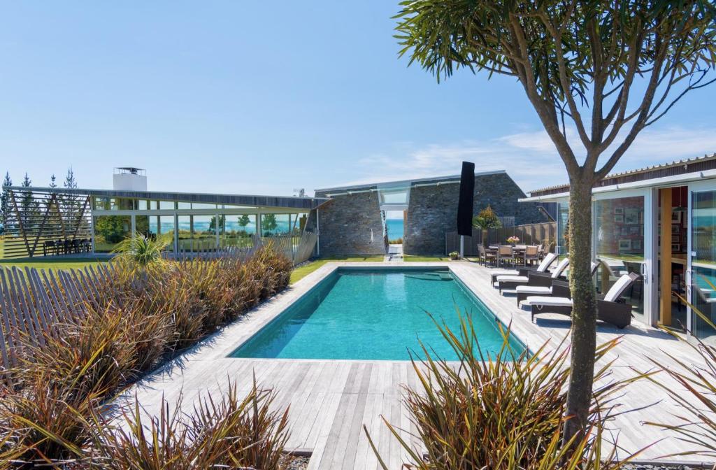 a swimming pool with lounge chairs next to a house at Kina Retreat - Luxury Nelson Getaway in Tasman