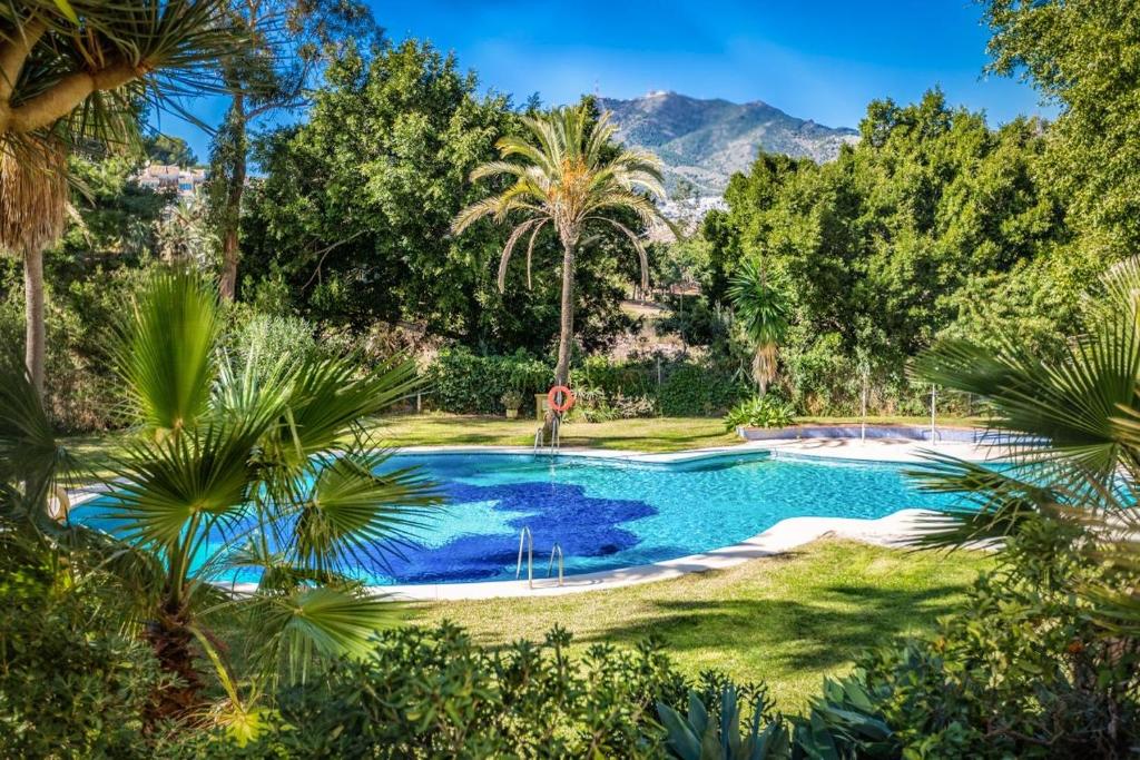 uma piscina num quintal com palmeiras em Benalmádena Marina Golf Appartement - Casa Valk em Benalmádena