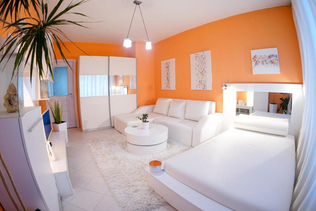 a living room with white furniture and an orange wall at Alex Botique in Varna City