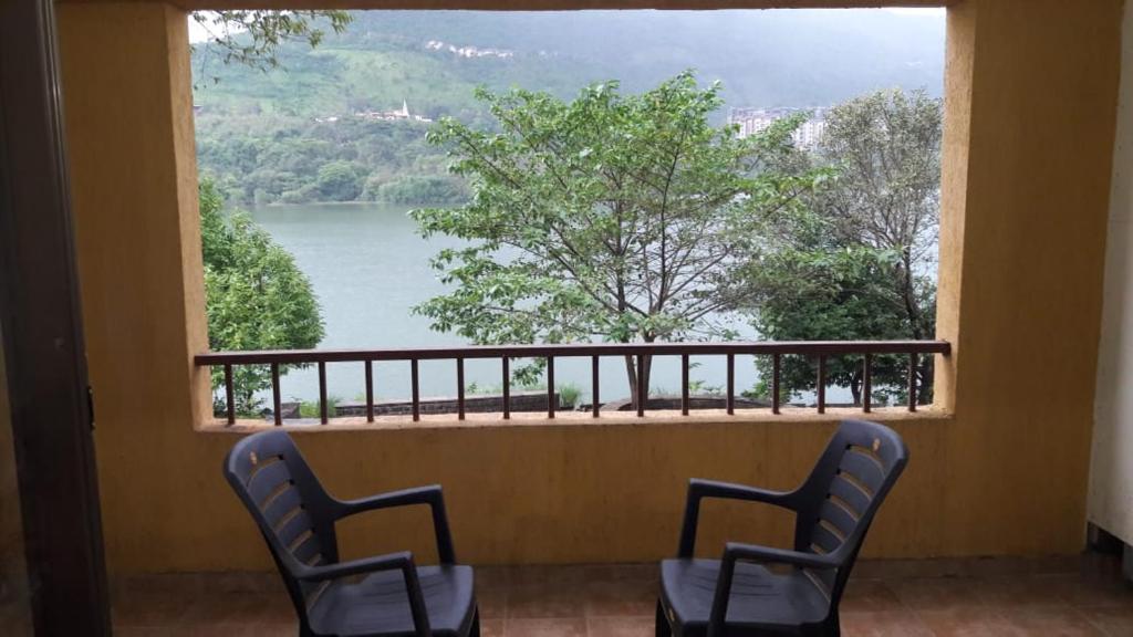 two chairs sitting in front of a window with a view at Studio Apartment On The Lake in Lavasa