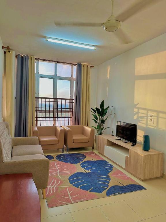 a living room with a couch and a computer on a rug at Normanis Homestay in Kota Bharu