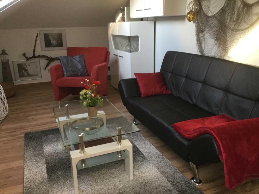 ビンツにあるFeWo Tinchen Prora Ruegenのリビングルーム(黒いソファ、赤い椅子付)