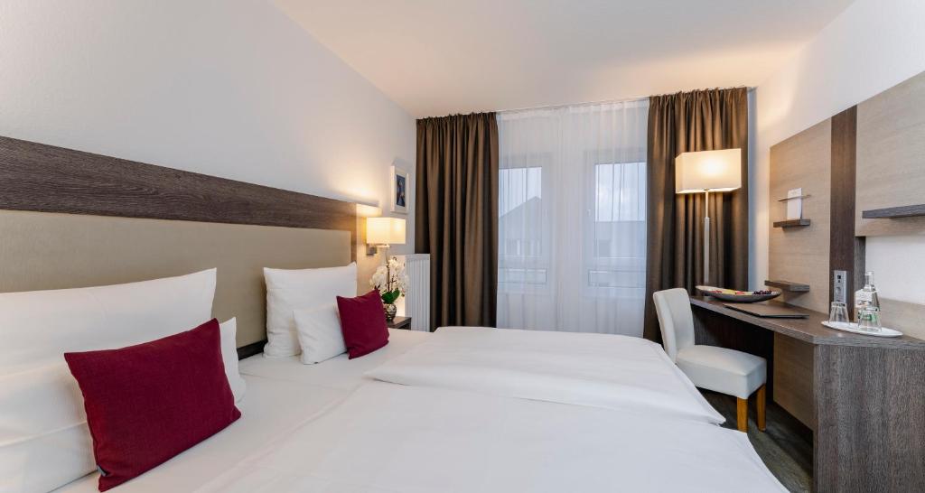 um quarto de hotel com duas camas e uma secretária em PLAZA INN Karlsruhe Nord em Karlsruhe