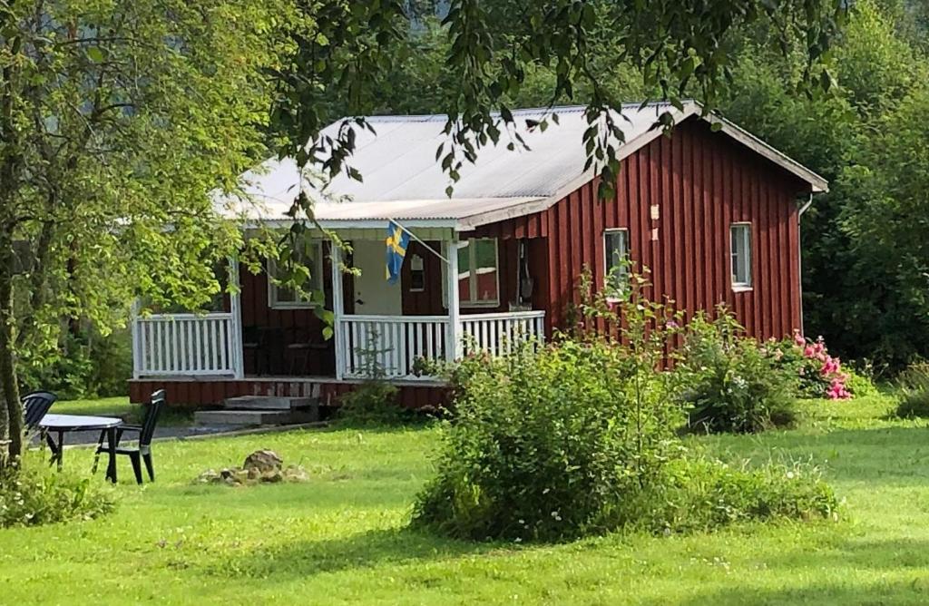 Villa Stuga في Hammarstrand: منزل احمر امامه مقعد