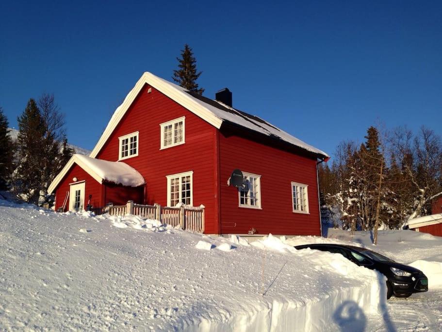 une maison rouge avec de la neige au sol devant dans l'établissement Kleiva 8 Skorovas, à Namsskogan