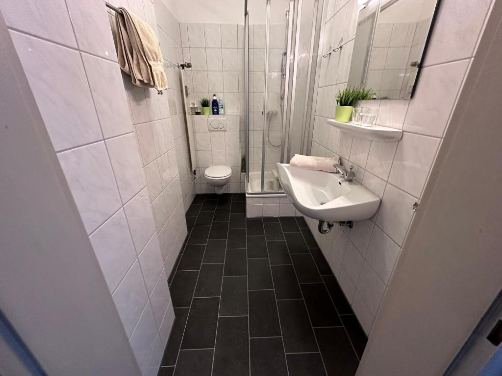 a white bathroom with a sink and a toilet at Einmaliger Rheinblick, fussläufig zur Messe in Düsseldorf