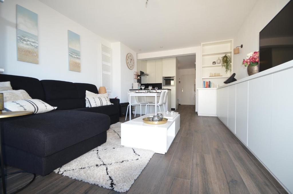 un soggiorno con divano nero e una cucina di An's seaview Middelkerke a Middelkerke