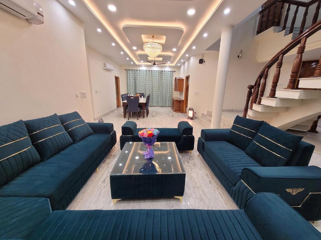 una sala de estar con sofás azules y una mesa. en Regalia Home Sapphire Stay, en Jammu