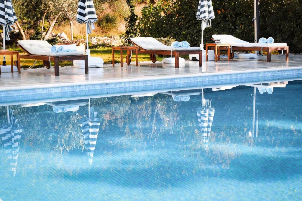 a swimming pool with chairs and umbrellas next to it at Villa Yanko, large pool stunning sea view in Tučepi