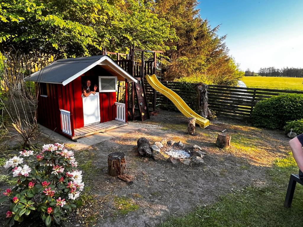 ein kleines rotes Spielhaus mit Rutsche in der Unterkunft Løkken Farm Holiday in Løkken