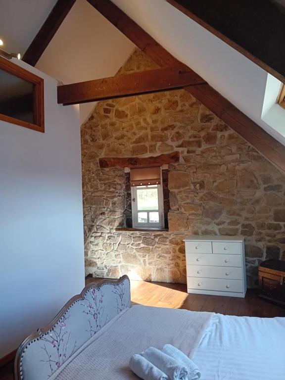 ein Schlafzimmer mit einem Bett in einer Steinmauer in der Unterkunft L'Annexe in Maël-Pestivien