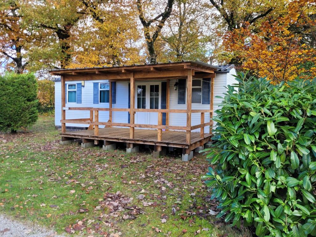 a cabin with a porch in a yard at Stacaravan 6 persoons - Camping Le Soustran in Neuvic