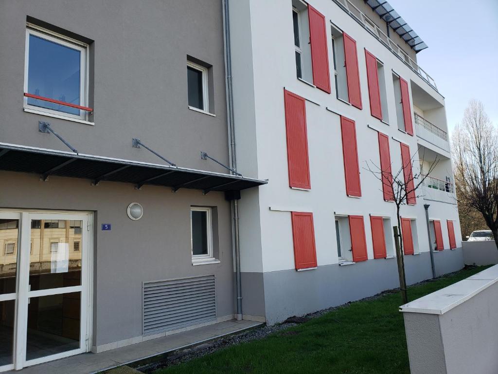 un edificio blanco con persianas rojas. en Charmant studio à 2 pas du tram en Nantes