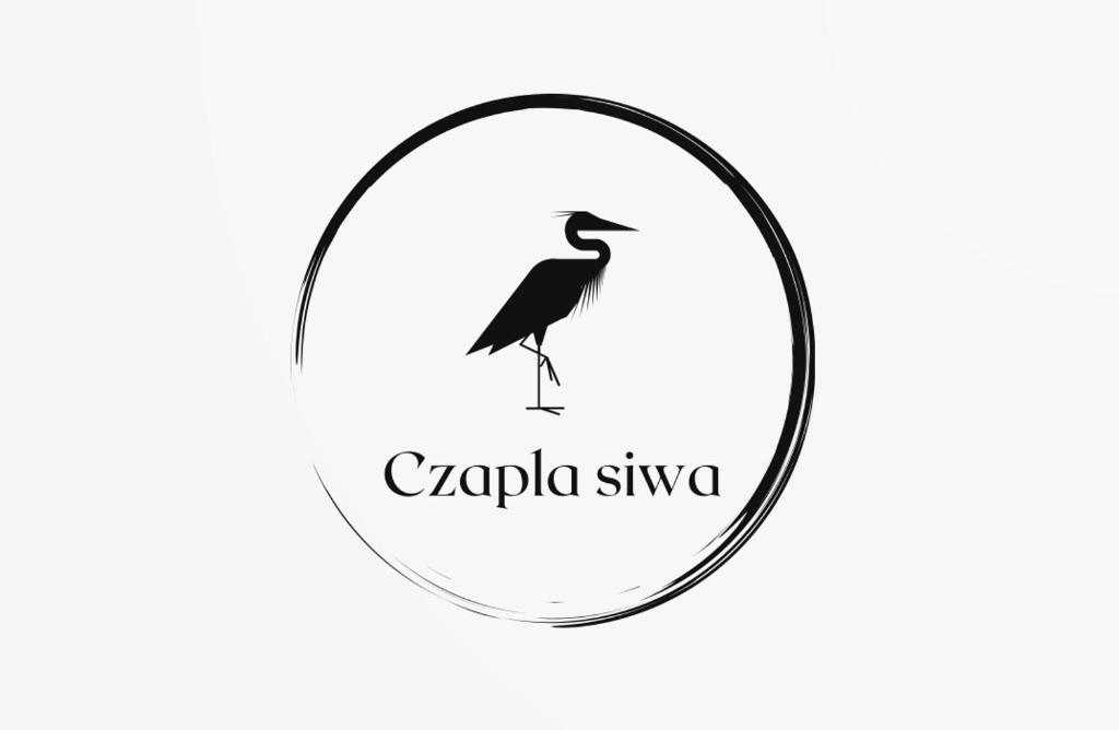 un pájaro negro de pie en un logo circular en Czapla siwa en Sztutowo