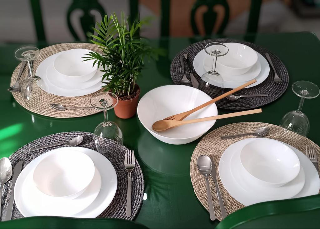 a green table with white plates and utensils on it at Nao Victoria in Gelves