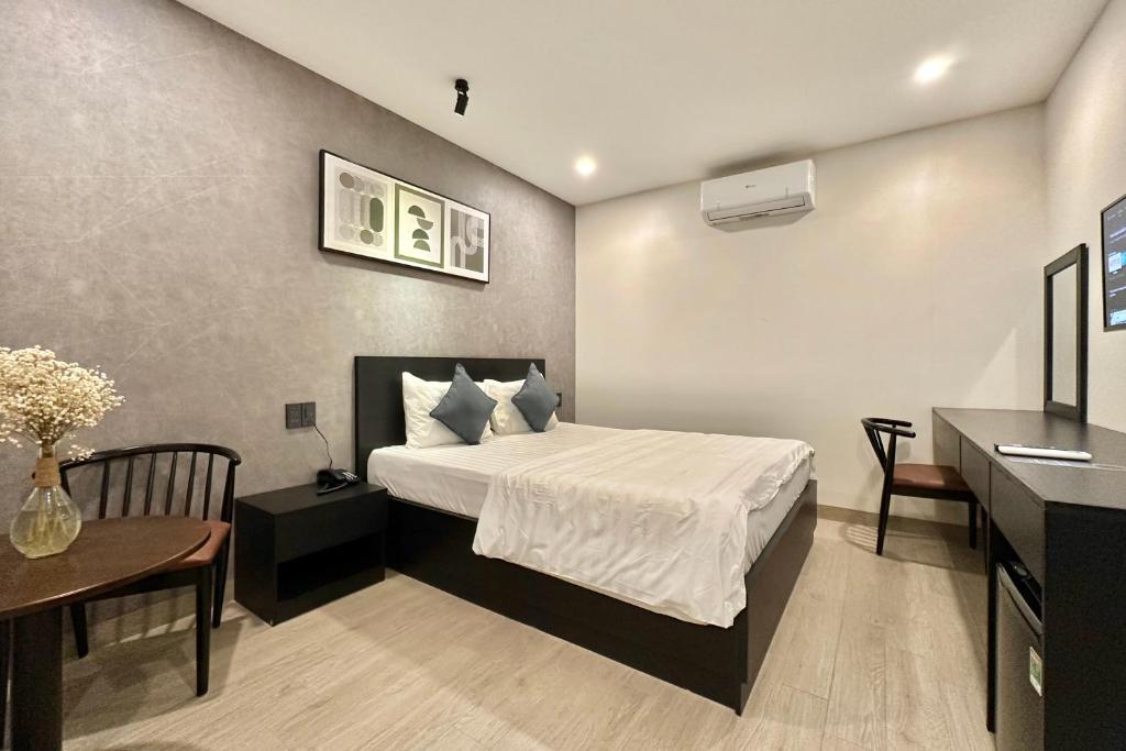 a bedroom with a bed and a table and a desk at G Hotel Sai Gon in Ho Chi Minh City
