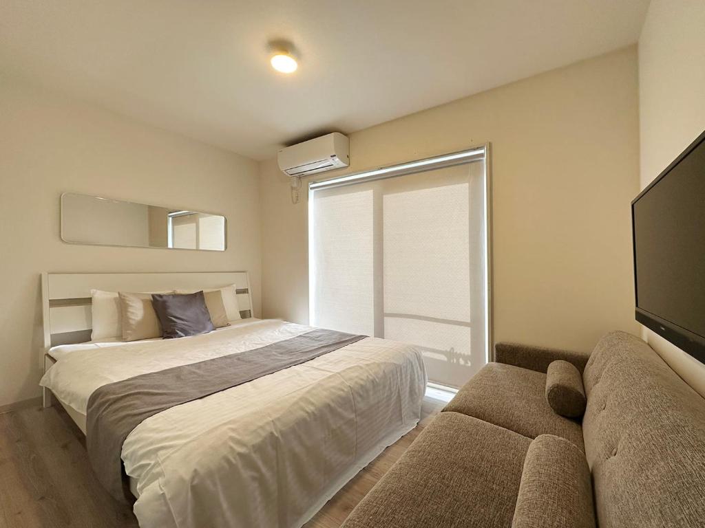 um quarto com uma cama, uma janela e um sofá em bHOTEL Yutori - Beautiful 1BR Apartment 6 mins walk to Station em Onomichi