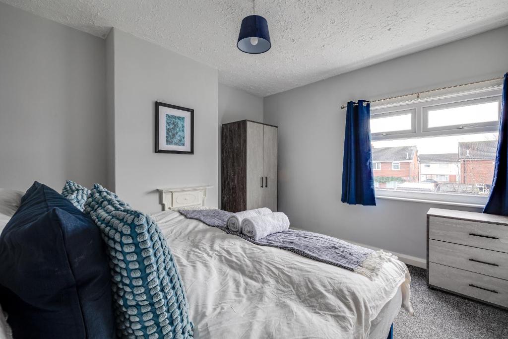 a bedroom with a bed with blue pillows and a window at Contract workers, Professionals, Families, Parking in Crewe