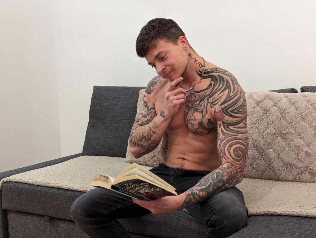 a shirtless man sitting on a couch reading a book at Large 4 room apartment in the center of Vienna in Vienna