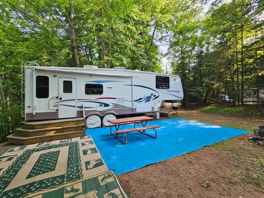 a white rv parked in a yard with a blue rug at The Mountaineer (Presque Isle Campground #4) in Presque Isle