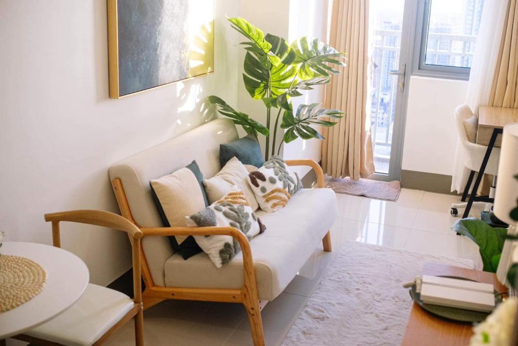 a living room with a white couch and a plant at Condo at Greenfield in Manila