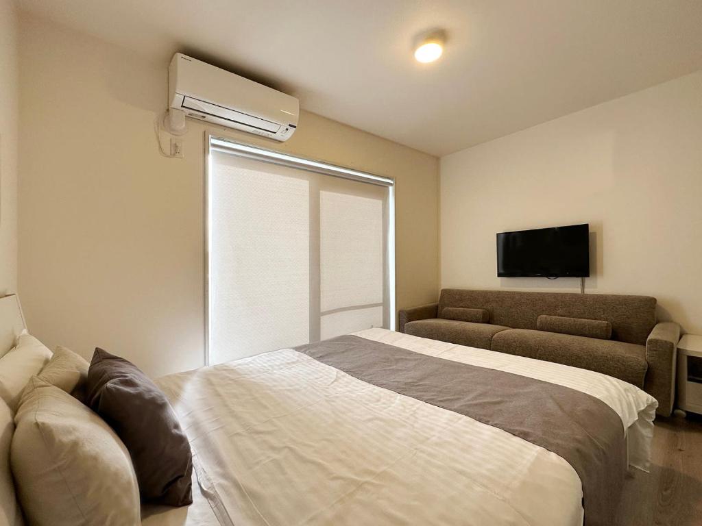 尾道市にあるbHOTEL Yutori - Cozy Nest in Onomichi City for 3ppl near the Stationのベッドルーム1室(ベッド1台、ソファ、窓付)