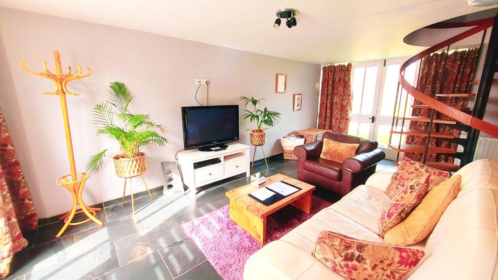 uma sala de estar com um sofá e uma televisão em Cader Mountain View Cottage with Hot Tub in Snowdonia em Dolgellau