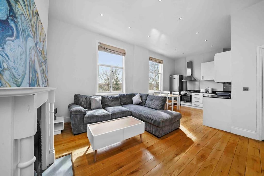 a living room with a couch and a kitchen at Queen’s Park, Spacious 3 Bedroom Flat in London