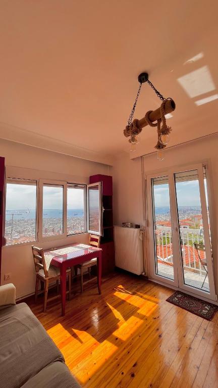 een woonkamer met een tafel en een aantal ramen bij Endless view in Thessaloniki