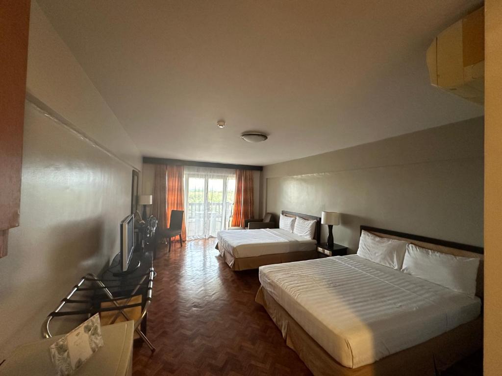 a hotel room with two beds and a television at H 109, Alta Vista De Boracay in Boracay