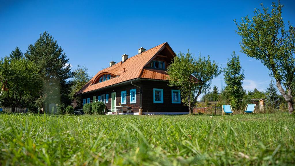 a house with two blue chairs in front of it at Apartmánová chalupa v Dvore u maliara in Bešeňová