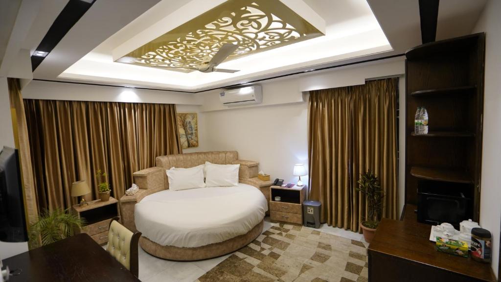 um quarto com uma cama, uma escrivaninha e uma televisão em Xpressmall Hotel near Dhaka Airport em Dhaka