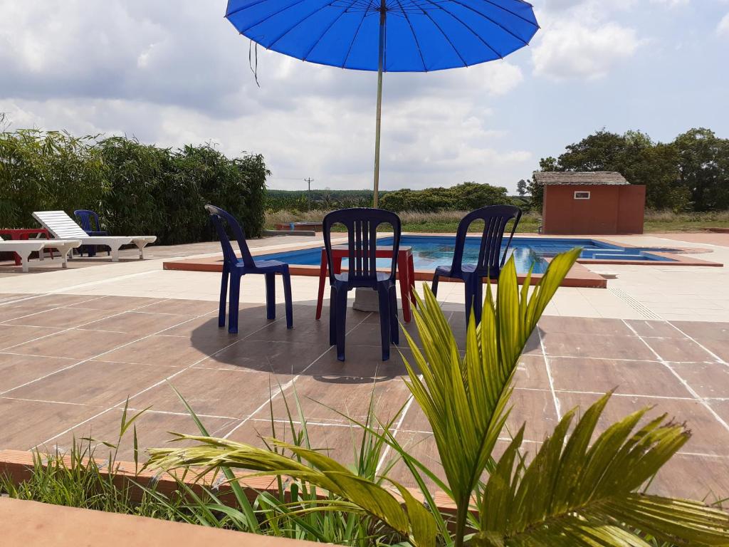 una mesa con 2 sillas y una sombrilla junto a la piscina en Koh Ker Hotel and Restaurant, en Phumĭ Mréch