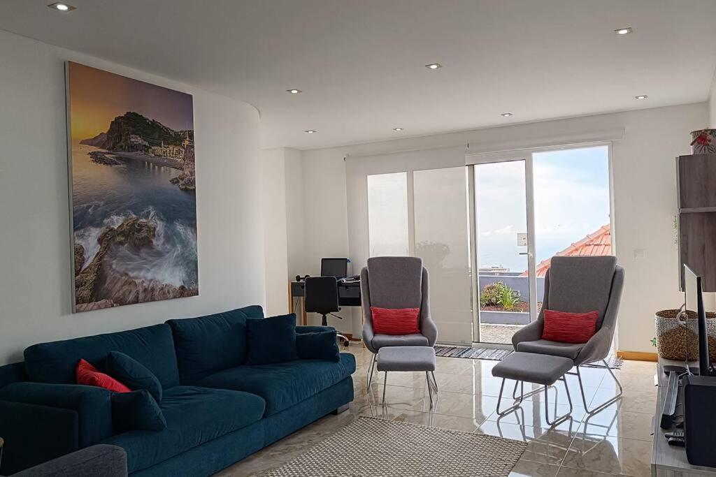 uma sala de estar com um sofá azul e duas cadeiras em Casa Monte Ponta do Sol SeaViews em Ponta do Sol