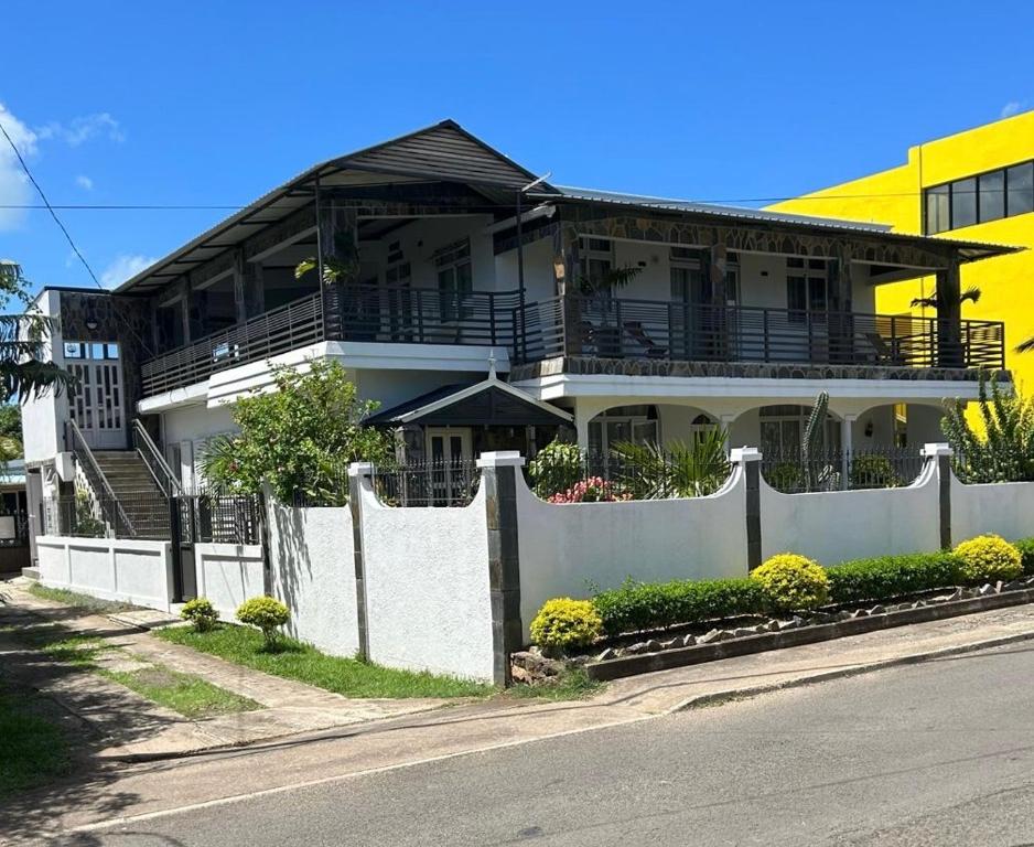 a large white house with a fence in front of it at L'oiseau vert apartments in Rodrigues Island