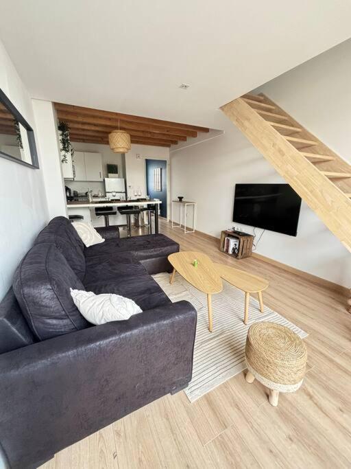 un salon avec un canapé noir et une table dans l'établissement La casa Rogatienne, à deux pas de La Rochelle, à Saint-Rogatien