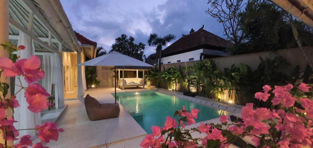 a swimming pool in a yard with pink flowers at La Dolce Villa in Seminyak