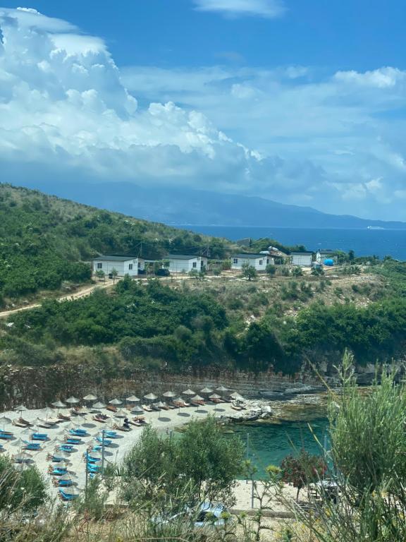 uma praia com guarda-sóis e cadeiras e o oceano em Sun n' Blue Villas em Sarandë