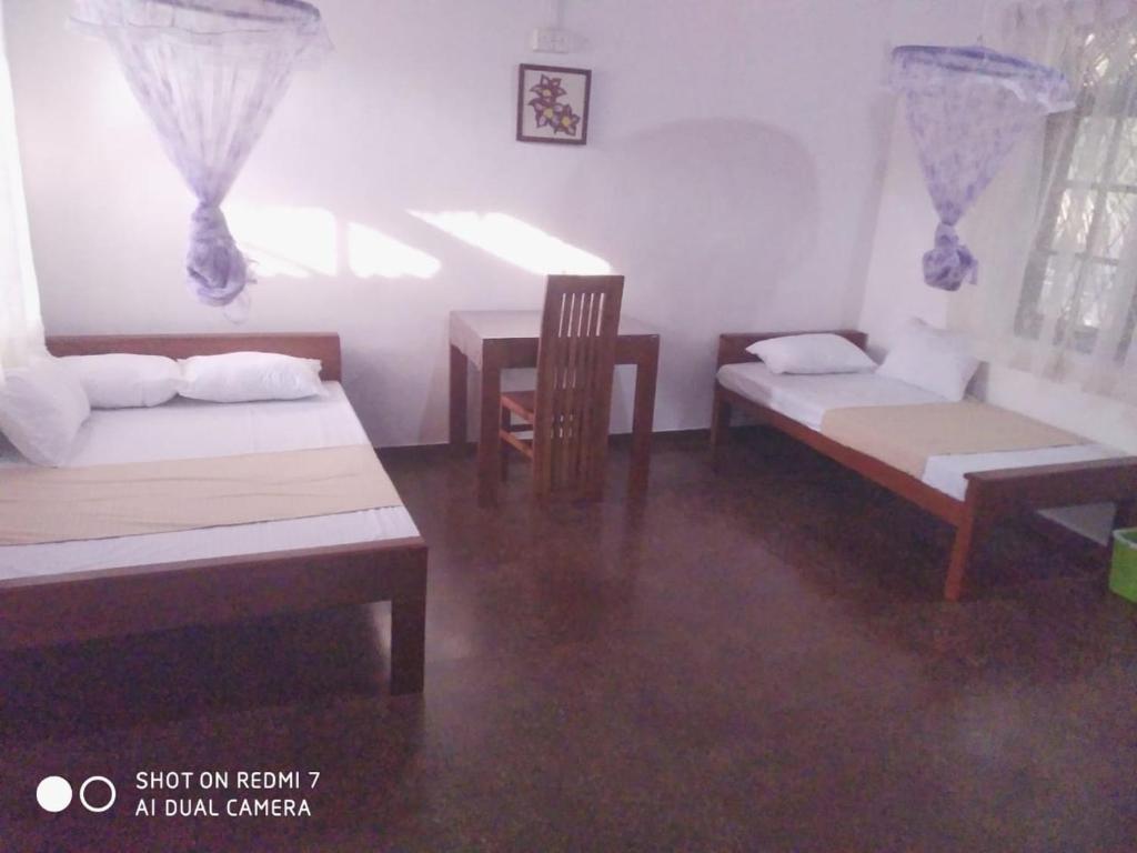 a room with two beds and a table and chairs at Leisure Home Human Care Center in Gonawala