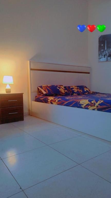 a bedroom with a bed and a night stand with a light at Live Like A Family Home away from Home near Manila Super Market Opposite SAHARA Center near Al Nahda Park NMC Center Sharjah in Sharjah
