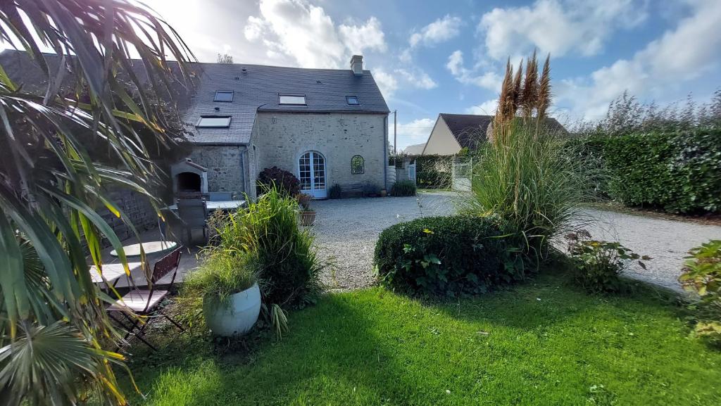 una casa con un cortile con erba e piante di Le So Sweet, maison avec jardin, baby foot, flipper, table de ping pong, à 1km à pied Omaha beach et près Port en Bessin a Sainte-Honorine-des-Pertes