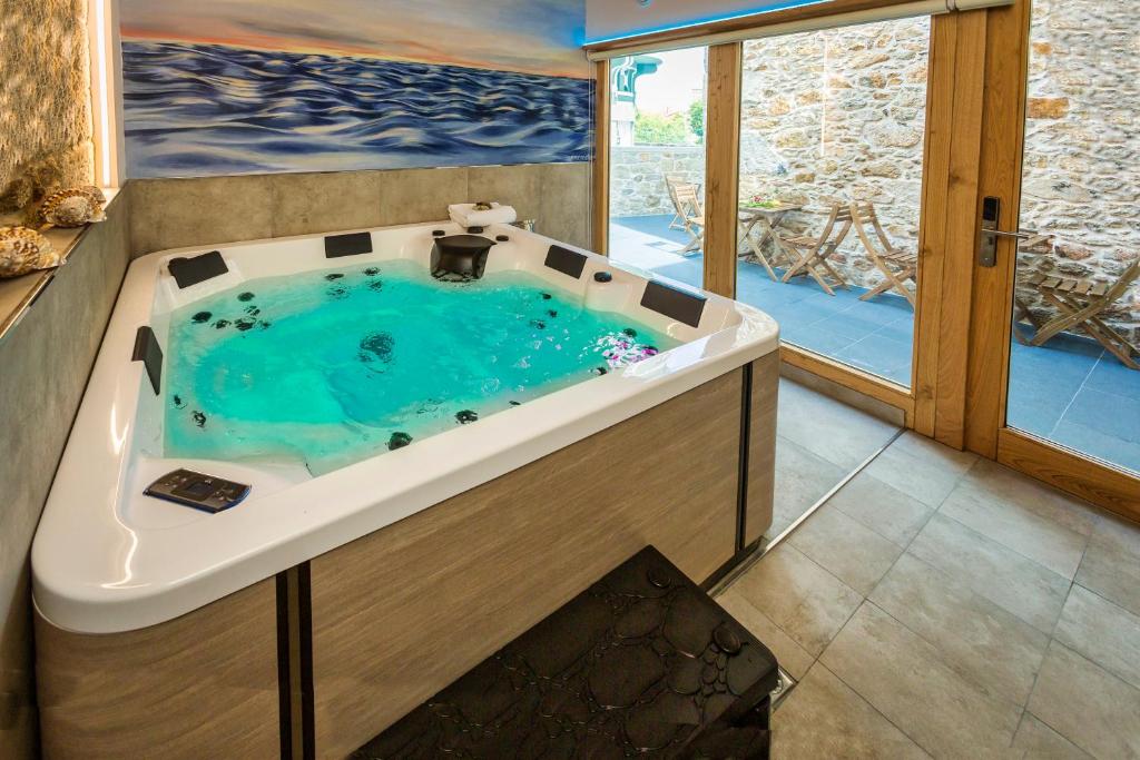 a bathroom with a jacuzzi tub with blue water at A de Lucía in Muxia