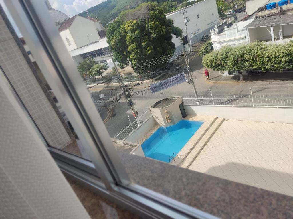 a view of a blue pool from a window at Solar Hotel in São Fidélis
