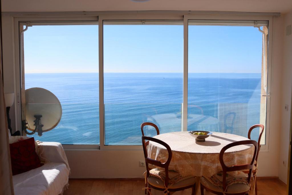 mesa y sillas en una habitación con ventana grande en Magnifico apartamento con vistas al mar, en Alicante