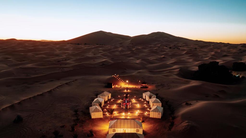 an aerial view of a desert with tents in the sand at Tiziri Camp in Merzouga