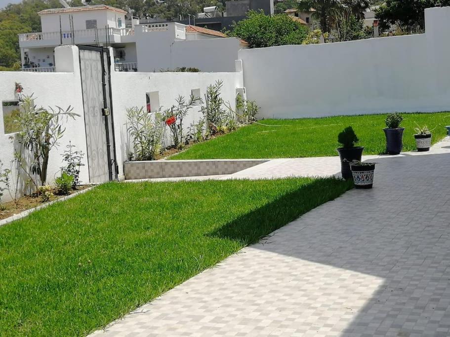 a grassy yard with a white fence and a sidewalk at Villa Vue sur Mer in Tabarka