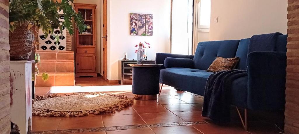 a living room with a blue couch and a table at Posada Puente Romano in Sedella