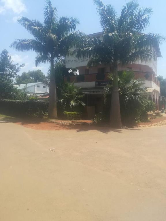zwei Palmen vor einem Gebäude in der Unterkunft Alwali Guest House in Mumias