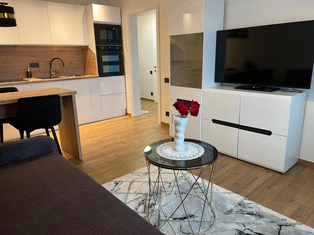 a living room with a table with a vase with roses on it at Apartamentai JOLA in Vilkaviškis